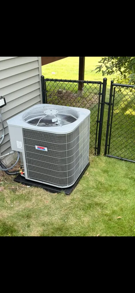 New HVAC unit with fan on a gravel surface in Maple Grove