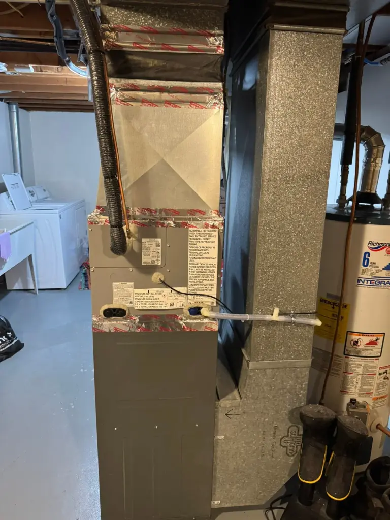 Furnace and ductwork with water heater in a basement utility area